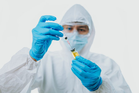 The doctor hold syringe, vaccine and wearing medical gloves, personal protective equipment or ppe, mask, goggle and suit to protect virus, medical, healthcare conceptの写真素材