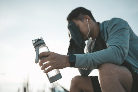 sport man sitting after running and holding water bottle drink. Sport thirsty and resting after...