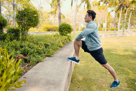 Attractive young man stretching in the park before running. Young man workout before fitness training at the park. Healthy and exercise young man warming up.の写真素材