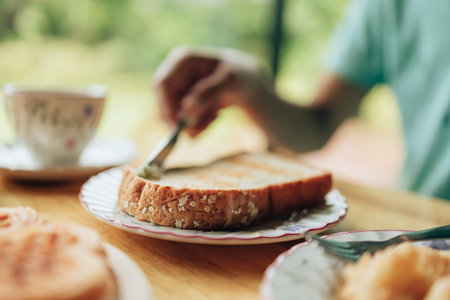 Knife spreading butter on toast bread in hands in the morning breakfast. Coffee and dessert concept.の写真素材