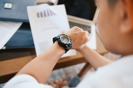 businessman looking at his watch on his hand, watching the time while working in office.