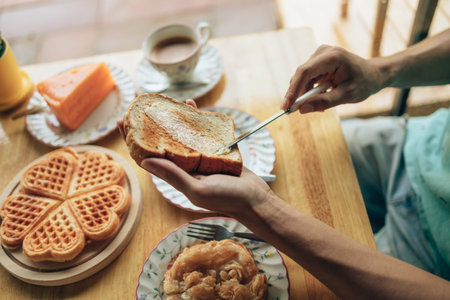 Knife spreading butter on toast bread in hands in the morning breakfast. Coffee and dessert concept.