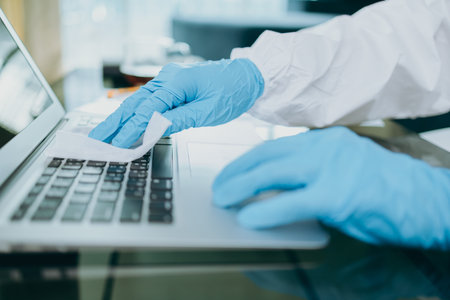 Scientists are cleaning labtop by alcohol and tissue after checking and testing virus on labtop at...