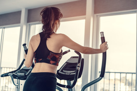 young women  using elliptical trainer in fitness gym.