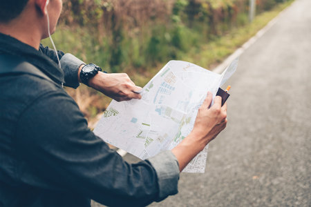 man with backpack hold map checking time the bus and he and walking on the road in forest. Backpack...