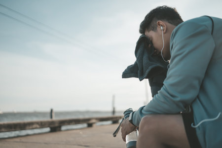 sport man resting after a running and wipe the sweat by towel and hand hold water bottle. sport and...