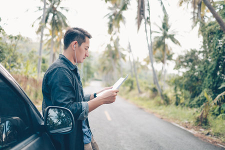 A man with backpack hiking read a map side car on the road in forest. Backpack travel concept.