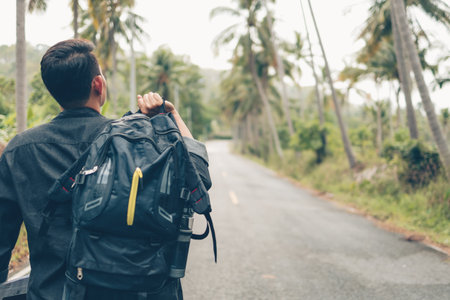 rear view of man with backpack hiking and walking on the road in forest. Backpack travel concept.の写真素材