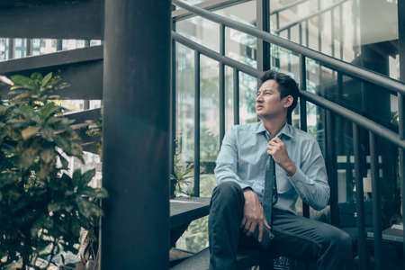 Unemployed people are tired on hot days using mobile phones to search for jobs, interview. Quitting a job, businessman fired or leave a job concept.の写真素材