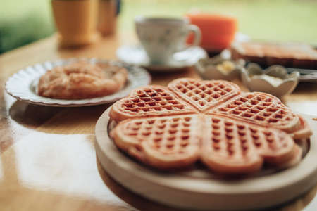 Hand pick  piece fresh waffles on wood plate. Waffle and dessert concept.の写真素材