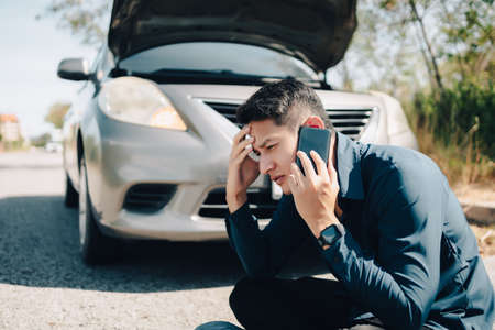 young man calling,  texting for car service on roadside assistance after broken car. Car broken, car breakdown concept.の写真素材