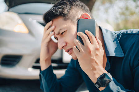 young man calling,  texting for car service on roadside assistance after broken car. Car broken, car breakdown concept.の写真素材