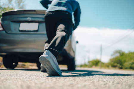 Man pushing a broken car breakdown on the road hot day. Car broken concept.の写真素材