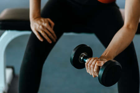 Fitness girl lifting dumbbell in fitness gym. Fitness workout and muscle concept.の写真素材