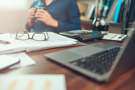 Glasses on data sheet in the office desk. Calculator with accounting report and financial statement on desk.の写真素材
