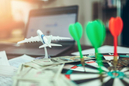 model airplane and dart board has dart arrow hitting of a shooting target and money coin for business targeting and good success.の写真素材