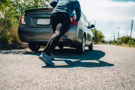 Man pushing a broken car breakdown on the road hot day. Car broken concept.の写真素材