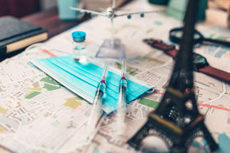 Vaccine, syringe and mask on map. Important equipment before traveling during COVID concept.の写真素材