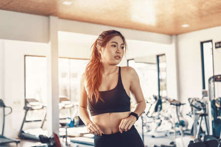 fitness women check her body with mirror at fitness gym.の写真素材