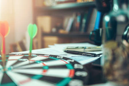 Pen on data sheet and dart board has dart arrow hitting of a shooting target for business targeting and good success.の写真素材