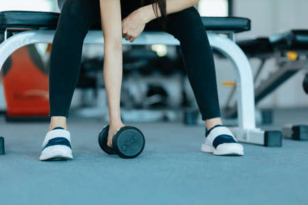Fitness girl lifting dumbbell in fitness gym. Fitness workout and muscle concept.の写真素材