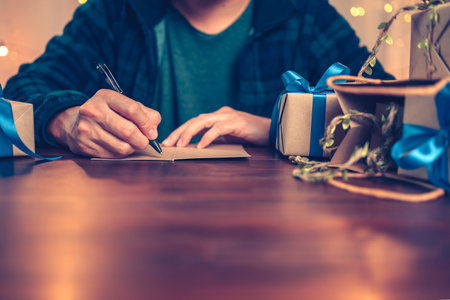 Hands writing greeing card and gift box, present on the table and light of bokeh background....