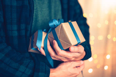 Hands holding gift box, present on the table and light of bokeh background. Valentine's Day, Christmas, Birth day, New year and Anniversary concept.の写真素材