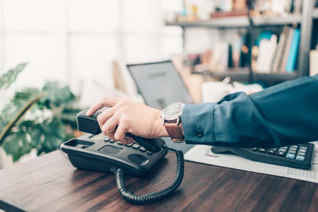 businessman dialing desk phone in the office. Telephone dialing ,contact and customer service.の写真素材