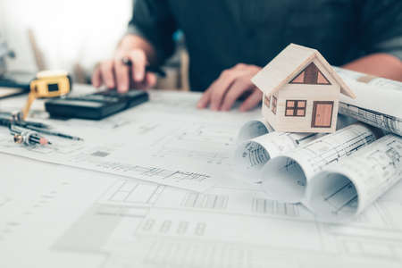 Mini model house on roll blueprint plan and architector use calculate for check cost drawing on blueprint background. House Architect design and engineer concept.の写真素材