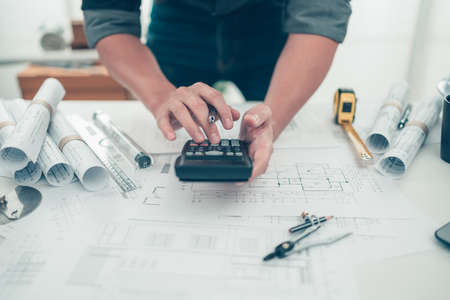 Architect engineer use calculator for calculate drawing design working on bueprint. House planning design and construction concept.の写真素材