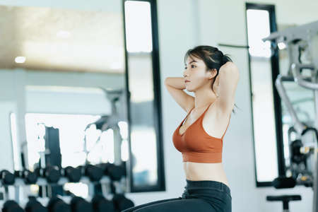 Asian woman in sportswear training sit up at fitness gym. Fitness and workout concept.の写真素材