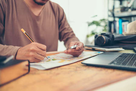 A man hold compas and checking road map and world map befor travel. Travel , Adventure and Discovery concept.の写真素材