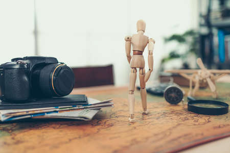 Wood doll walking on world map and other accesories for travel on the table.の写真素材