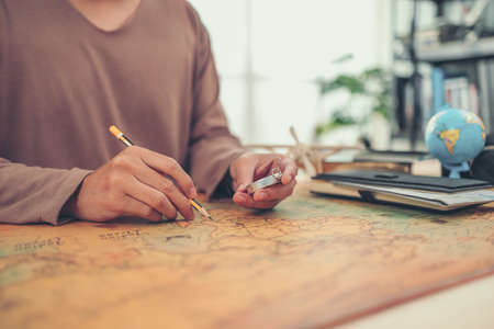 A man hold compas and checking road map and world map befor travel. Travel , Adventure and Discovery concept.の写真素材