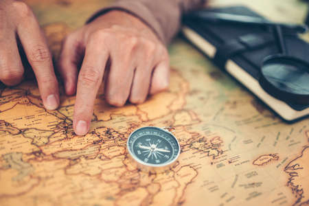 Tourist planning vacation, holiday with the help world map and compass. Man's hand marks route on map and using pins and rope. Travel concept.の写真素材