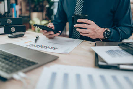 Accountant drink coffee and working on company data, document and report on desk office. Accounting business concept.の写真素材