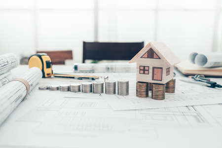 Mini model house and coin stack like a stair  on blueprint house plan design. Cost Architect and engineer concept.の写真素材