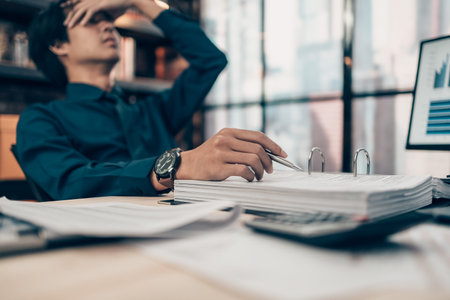 Serious Investors have a headache hold pen  working  on the desk.  Accounting and  Financial...