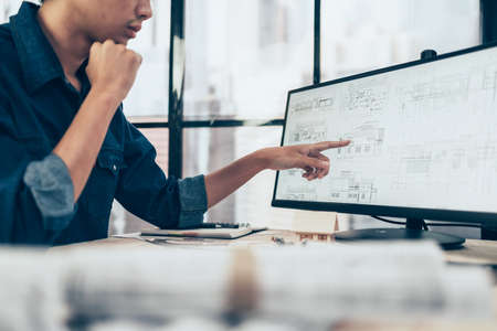 Architect engineer read drawing design and hand pointing to monitor screen. House planning design and construction concept.の写真素材