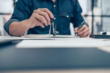 Architect using divider compass working on blueprint and make a note on book. Construction concept. Engineering toolsの写真素材