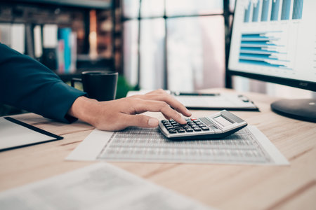 Investors working on desk office and using a calculator to calculate balance, projit, currency and...