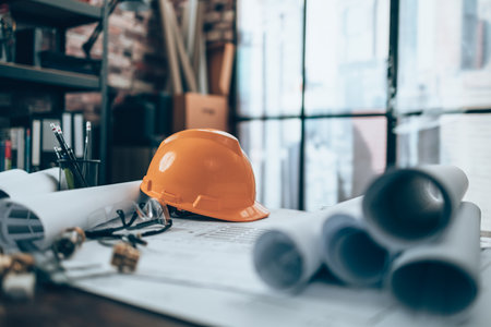 Engineer safety helmet with drawings inspection on the office desk and Calculator, triangle ruler, safety glasses, compass, vernier caliper on Blueprint. Engineer, Architect, Industry and factory concept.の写真素材