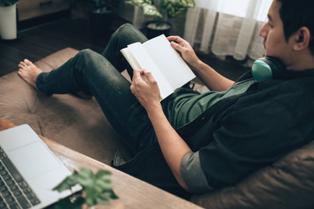 Men hand holding Book and reading with blank paper on sofa at home. Relax home concept.