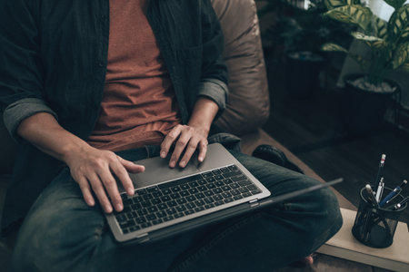 Men using laptop to working, play game, listen music or relaxing on sofa at home. Relax home concept.の写真素材