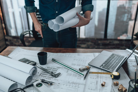 Engineering holding paper roll drawings in the office and Calculator, triangle ruler, safety...