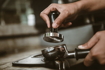 Barista using a tamper to press ground coffee into a portafilter. Coffee maker concept.の写真素材