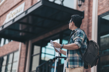 Tourists hold maps to find attractions, restaurants or hotels while waiting for their bus or passenger boat and the background is a big city.  backpackers and travel concept.の写真素材