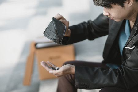 Employees fired or resigned from the company are opening their wallets and holding coins in their hands.Unemployed, hiring job, quitting job concept.の写真素材