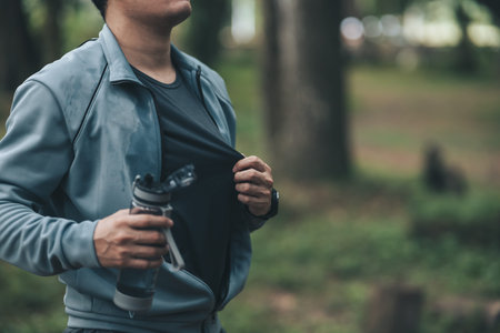 Young sport man drink water after jogging, running in the park. Sport thirsty and resting after...
