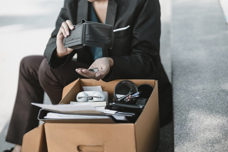 Employees fired or resigned from the company are opening their wallets and holding coins in their hands.Unemployed, hiring job, quitting job concept.の写真素材